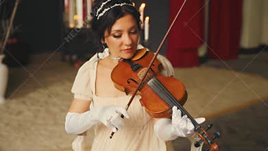 Beautiful woman professional musician plays a wooden on the violin. Pretty face girl violinist musician plays at event