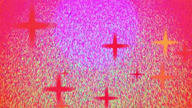 Sand grains of various beautiful colors fly around against a blushing red background.