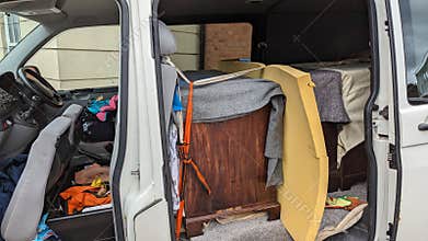 An open van transporting secured wooden furniture by courier