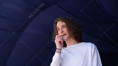 portrait of a young guy blowing his nose from an allergic runny nose into a napkin