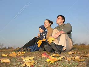 Family sit with autumn leaves