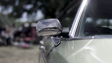 Close up shot of shiny side view mirror on a classic car