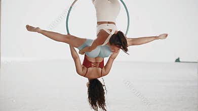Two women show tricks on a aerial hoop