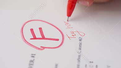 Professional school or college teacher grades a homework exam papers of students. Woman grades test with F mark and