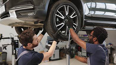 Two mechanics working on car wheel in auto repair shop