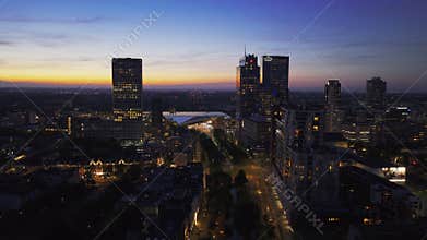 Enchanting aerial view of Rotterdam's cityscape during twilight, with glowing skyscrapers and city lights against a