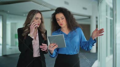 Professional women using phone and tablet. Managers in modern workspace closeup.