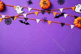 Happy Halloween concept. Flat lay composition with pumpkins, spiders, ghosts, webs, bunting garland on purple background