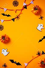 Halloween frame of bunting, ghosts, pumpkins, web, bats, spiders on orange background. Flat lay, top view, copy space