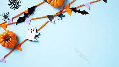 Happy Halloween banner deign with garland, pumpkins, ghost, bats, spiders on pastel blue background