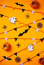 Creepy Halloween composition with ghosts, spiders, bats, bunting flag garland, pumpkins on orange background. Flat lay, top view,