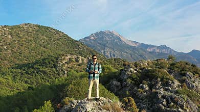 Videographer hiking mountain controlling drone