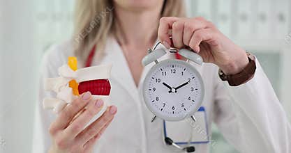 Doctor explains anatomy of spine and holds alarm clock