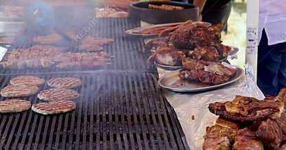 The meat is grilled on the grill and open fire. Male hands of chef with a tongs for the grill check the meat at the ready.