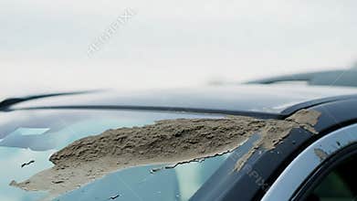 A large lump of dirt falls onto a clean car windshield in an unexpected moment of nature\'s surprise