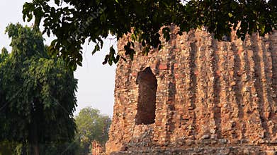 View of the unfinished one-story tower, Alai Minar, amidst trees and gardens.