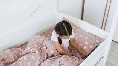 Little girl excitedly places tooth under pillow for fairy