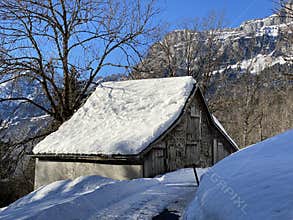 Old traditional swiss rural architecture and alpine livestock farms in the winter ambience over the Lake Walen or Lake Walenstadt
