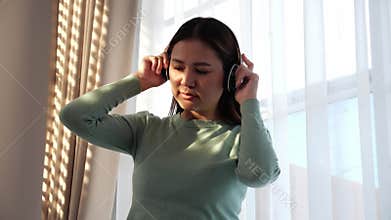 Portrait happy young woman wearing headphones listening music while standing with fun and enjoy.