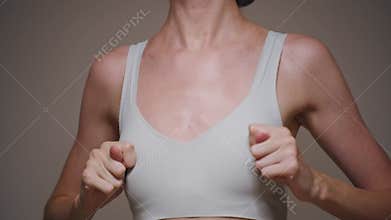 A young woman checks her breasts and shows a funny gesture