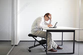 Young man is bent over his tablet.Bad sitting posture at work