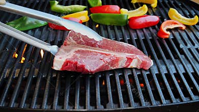 T- bone steak put on cast iron grill barbecue. Slow motion