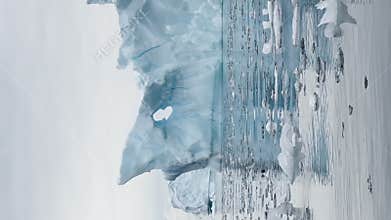 Large cruise ship in the bay near the Antarctic, a huge iceberg on mountains, the southern ocean of Antarctica at sunset