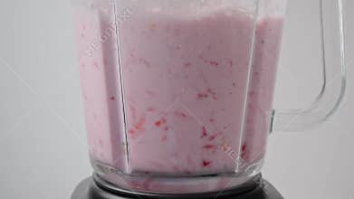 Fresh strawberry and milk into blender cooking milkshake, smoothie. Slow motion.