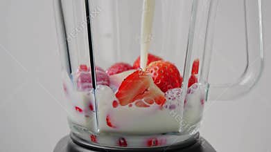 Pouring milk into blender with strawberry for cooking milkshake. Slow motion. Smoothie