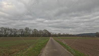 Car ride to the horizon between fields and meadows and clouds