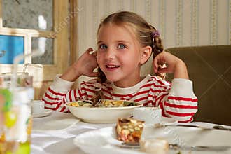 Cute smiling little girl sitting at the dinner table