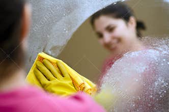 Woman smiling cleaning a mirror