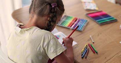Concentrated girl draws picture with colored felt-tip pens