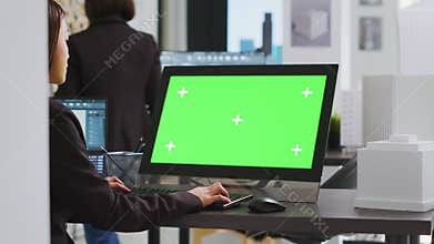 Cad specialist using computer with greenscreen at office desk