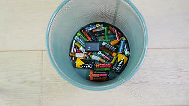 Ternopil, Ukraine - January 15, 2024: A person throws used batteries into office garbage bin