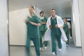 Doctors In Scrubs Running Through Hospital Corridor
