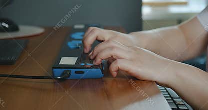 Close-up hands of person with blindness disability using computer keyboard and braille display