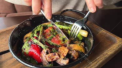 eat grilled vegetables Close up side view of woman eating grilled chicken salad from wooden bowl.