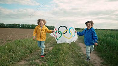 Paris, France - 18 May 2024: Little boys, sport fan kids running with Olympics Games flag waving in wind on countryside