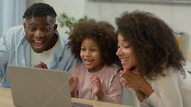 Happy excited winners African American family father mother with little child daughter girl kid celebrate laptop victory