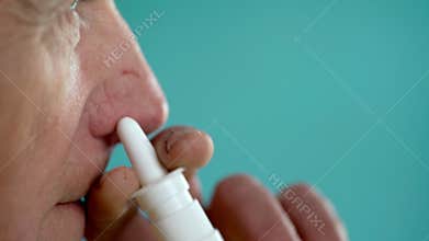 Close-up of an elderly man using a nasal spray to treat allergies and runny nose