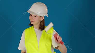 Worker in uniform demonstrates wallpaper knife and roller