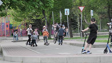Children enjoying leisure time riding scooters and skateboards on city street