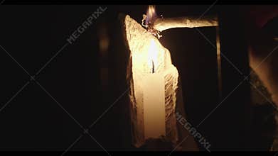 Candle glowing in darkness, flame light at night. Candlelight, background with dark, black elements.