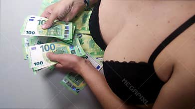 A woman in underwear counts 100 euro bills, breasts in a bra