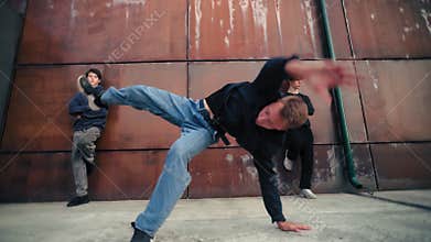 B-boy dancing on ground in city street, performing tricks and modern choreography, emotional dance