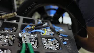 Man works with car wheel near weights for balance