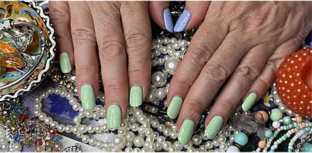 women's hands with painted nails on a background of jewelry