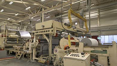 Worker walks to controls paper press machine with drums