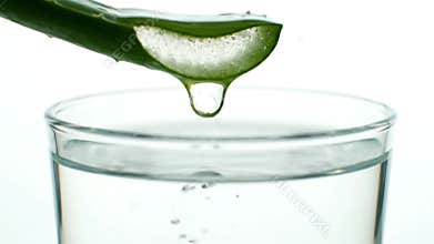 Close Up of Sliced Aloe Vera Leaf Dripping Gel into Glass of Water on White Background Health and Wellness Concept for